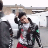 a man in a leather jacket is standing next to another man in a white shirt .