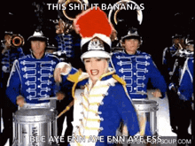 a woman in a marching band uniform is standing in front of a drum set and says this shit it bananas