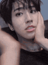 a close up of a young man 's face with his hand on his chin .