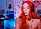 a woman wearing red wig and pink headphones is standing in front of a shure microphone
