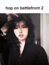 a woman is standing in front of a wall with the words `` hop on battlefront 2 '' written on the bottom .