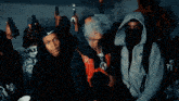 a man in a hoodie is smoking a cigarette while another man looks on