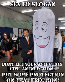 a man in a suit stands next to a giant condom