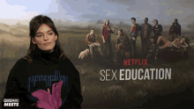 a woman stands in front of a poster for sex education