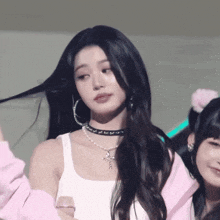a woman wearing a choker necklace and hoop earrings looks at the camera