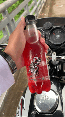 a person is holding a red bottle of sting soda