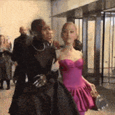 a woman in a pink dress walks with another woman in a black dress