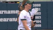 a woman in a softball uniform stands in front of a scoreboard that says talons 4 blaze 0