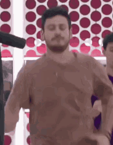 a man with a beard is dancing in front of a microphone in a room .