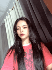 a woman wearing a red t-shirt that says ' univ ' on it takes a selfie