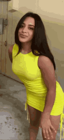 a woman in a neon yellow dress is standing in a parking garage .