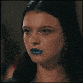 a close up of a woman with blue lipstick and earrings