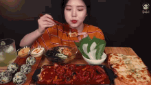 a woman is sitting at a table eating a variety of food with chopsticks