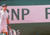 a man holding a tennis racquet in front of a bnp p logo