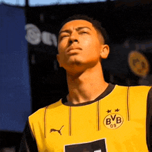 a young man wearing a yellow bvb jersey looks up at the sky