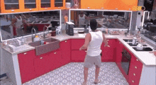 a man in a white tank top is dancing in a kitchen .