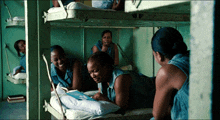 a group of women are laying on bunk beds and one of them is crying