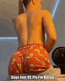 a shirtless man in red underwear is standing in front of a fan and a mirror .
