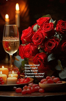 a bouquet of red roses next to a glass of wine