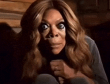 a woman with long hair is making a funny face while sitting on a couch .