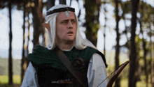 a man with white hair and ears is holding a bow and arrow in a forest