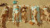 a group of women laying on striped towels on a beach