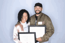 a man and a woman holding two framed papers one of which says ' world citizen in social media ' on it
