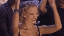 a woman is dancing in a crowd with her arms in the air and smiling .