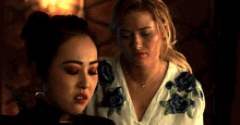 two women are standing next to each other and one is wearing a white shirt with blue roses on it