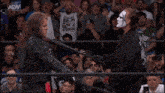 two men are wrestling in a ring with a crowd watching and a sign that says aew on it .