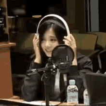 a woman wearing headphones sitting in front of a microphone