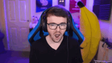 a man wearing glasses and headphones looks surprised in front of a banana