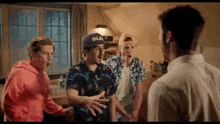 a group of young men are standing next to each other in a room and talking to each other .