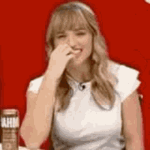 a woman is sitting at a table with a can of soda in front of her .