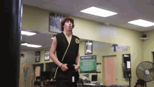a man in a black karate uniform stands in front of a mirror with a sign on the wall that says martial arts