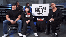 a group of people sitting in front of a sign that says hey ( ew )