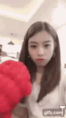 a woman in a white shirt is holding a red heart shaped stuffed animal .
