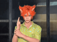 a man with orange hair and ears is wearing a green shirt and making a peace sign