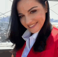 a woman in a red jacket and white shirt smiles