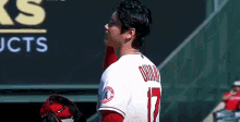 a baseball player is standing in the dugout with his glove on his head .