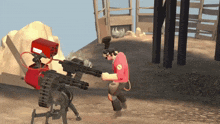 a man in a red shirt is standing next to a robot with a red box on it that says team fortress 2