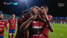 a group of soccer players wearing hisense jerseys are celebrating a goal