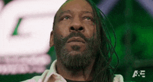 a man with dreadlocks and a beard is looking up in front of a green background .