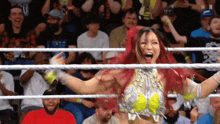a woman with red hair is in a wrestling ring surrounded by fans