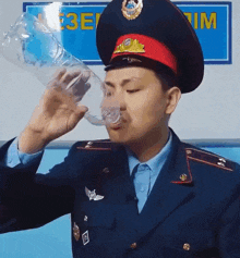 a man in a uniform is drinking from a plastic bottle