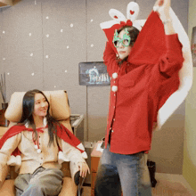 a woman wearing a santa cape stands next to another woman