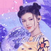 a girl with two buns on her hair is standing in front of a disco ball