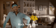 a man in a blue shirt is standing in front of a vase of yellow flowers and says rock hard pass
