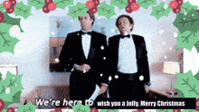 two men in tuxedos are standing next to each other with a christmas greeting