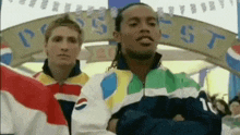 two men wearing pepsi jackets are standing in front of a pepsi sign .